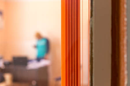 images from an office street, through a window with an orange curtain, silhouette of a man on a blurred backgroundの写真素材