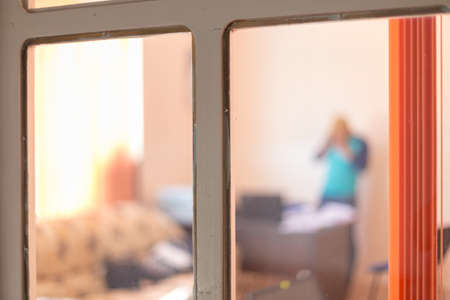 images from an office street, through a window with an orange curtain, silhouette of a man on a blurred backgroundの写真素材