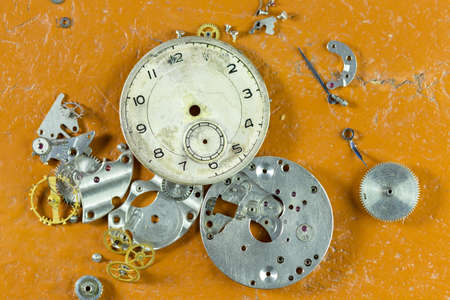 Spare parts from mechanical watches on the table, yellow backgroundの写真素材