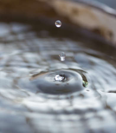 Drops from the tap fall into a bucket of water. Tap water.