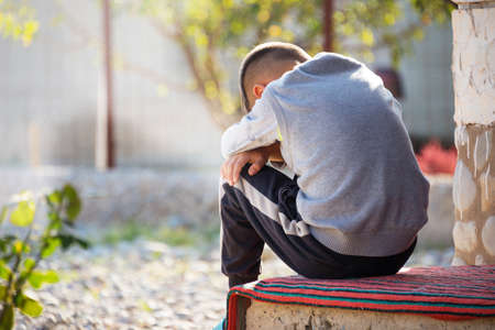 offended child sits and cries on the streetの写真素材