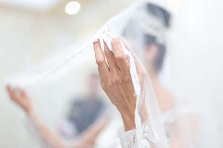 Close up of bride's hands holding white dressesの写真素材