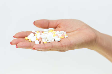 in the girlâs hand a lot of pills on a white backgroundの写真素材