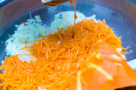 A woman's hand holds a piece of fresh pumpkin and rubs it on a metal kitchen grater.の写真素材