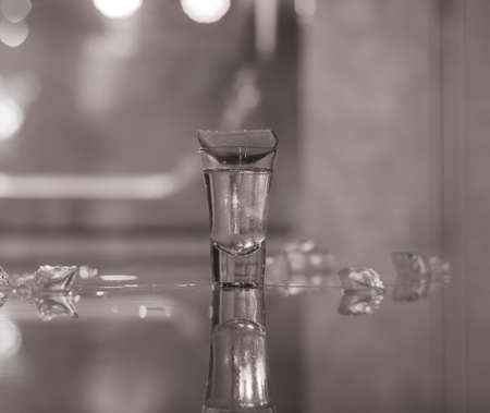 glasses of silver tequila, a slice of lime and pieces of ice on the tableの写真素材