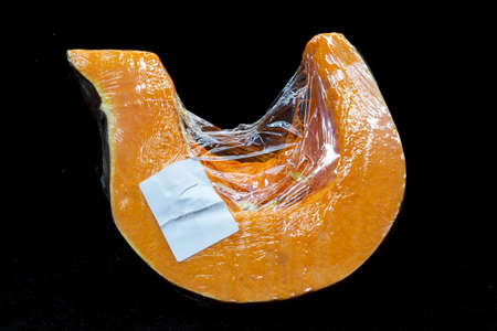 slice of pumpkin cut on a sticky film, close-up photo, protection against damage, isolated on a black backgroundの写真素材
