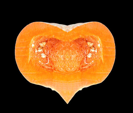 Sliced orange pumpkin in the shape of a heart. Isolated on a black background.の写真素材