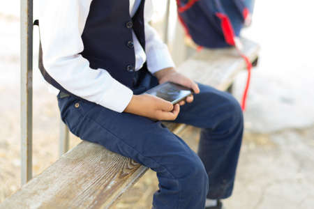 Young boy play online games on a smartphone. Beautiful teenager use phone from sideの写真素材