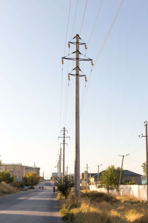 Concrete pillar power lines with steel traverses, porcelain insulators and high-voltage wires on a...