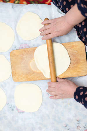 cook, female hand rolls the dough on a wooden board