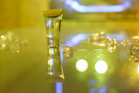 glasses of silver tequila, a slice of lime and pieces of ice on the tableの写真素材