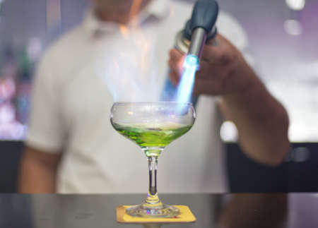 The bartender is lighting a cocktail, a cocktail is lit in a barの写真素材