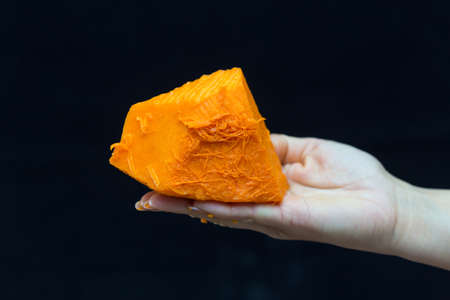 Female hand holds a piece of fresh pumpkin on a black backgroundの写真素材