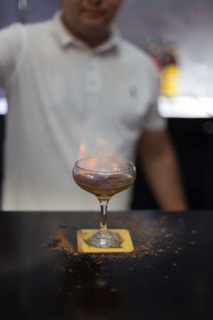 The bartender is lighting a cocktail, a cocktail is lit in a barの写真素材