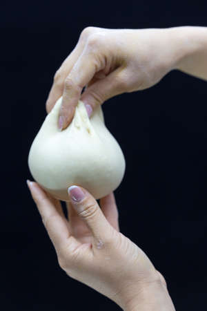 Baker's hands round dough on a black background.の写真素材