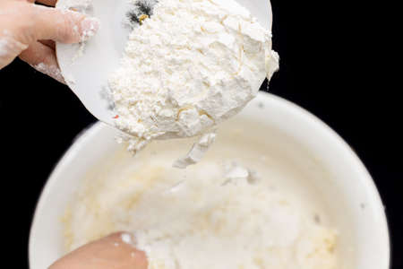Hands of the cook prepare the dough for bread on a black background. Restrained shot with flour.の写真素材