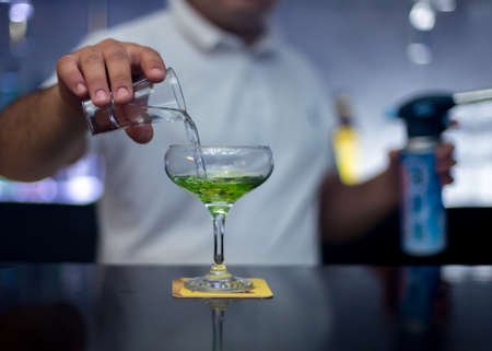 The bartender is lighting a cocktail, a cocktail is lit in a barの写真素材