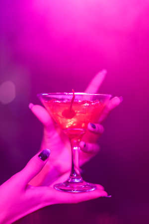 cocktail in the hand of a young girl in a nightclubの写真素材