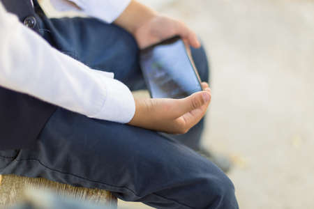 Young boy play online games on a smartphone. Beautiful teenager use phone from sideの写真素材