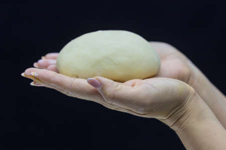 Baker's hands round dough on a black background.の写真素材