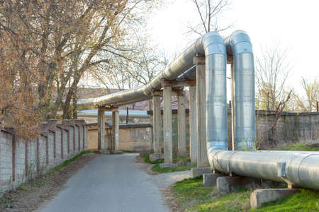 A pipeline above the ground that conducts heat to heat a city. City line in metal insulation in a residential quarter of the cityの写真素材
