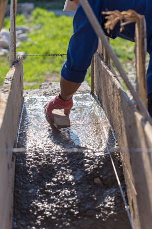 The male hand levels a cement mortar with a rake. Concrete foundation for homeの写真素材