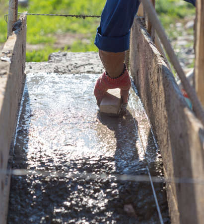 The male hand levels a cement mortar with a rake. Concrete foundation for homeの写真素材
