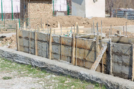 Formwork for the foundation of the house. Close-up of the foundation of a house made of concrete formwork blocks filled with mortar and reinforcementの写真素材