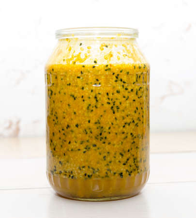 Therapeutic mixture with honey from sesame seeds, turmeric, caraway seeds and ginger on a glass jar on the tableの写真素材