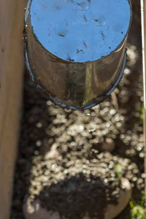 A man pours cement mortar from a bucket. Concrete foundation for homeの写真素材