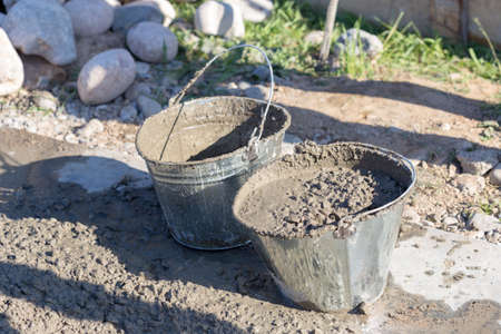 Manually mixing cement mortar with a shovel on a sheet of iron and loading into a bucketの写真素材