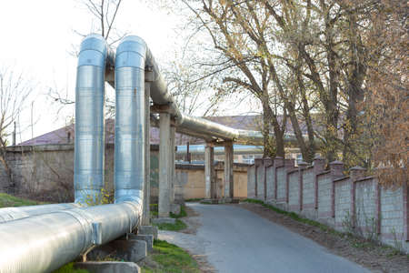 A pipeline above the ground that conducts heat to heat a city. City line in metal insulation in a residential quarter of the cityの写真素材