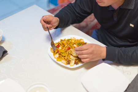 Man eating noodles in a cafe during lunch