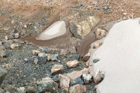 The last snow in the alps. Dirty snow on the rocksの写真素材