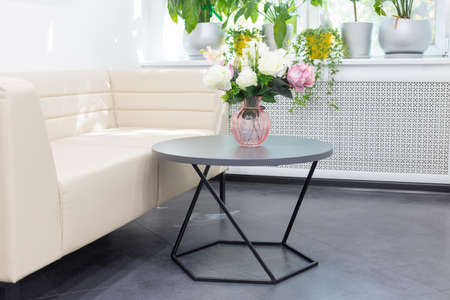 pink artificial flowers on a glass bottle, a bouquet of silk flowers on a white table next to a book and scentの写真素材
