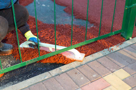 red rubber covering for the playground, the master smoothes the soft rubber crumb by hand. Soft covering for sports floors. Rubber mulch for safety and injury prevention.の写真素材