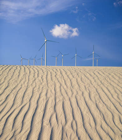 Digital composite image of large wind turbines over rippling sand dunes 
