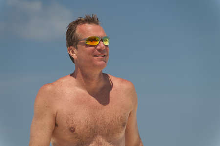 Shirtless man wearing yellow reflector sunglasses at the beach, Bahamas
