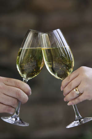 Two people hands clinking glasses of white wine の写真素材