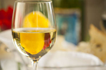 A single glass of white wine in a dinner setting の写真素材