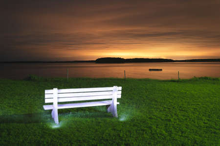 Light painted white bench iwith a dock floating in a bay at night, Maine, USAの写真素材