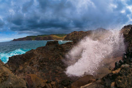 Water blown out from blow hole caused from a Pacific Ocean wave on the Maui coastline, Hawaii, USAの写真素材