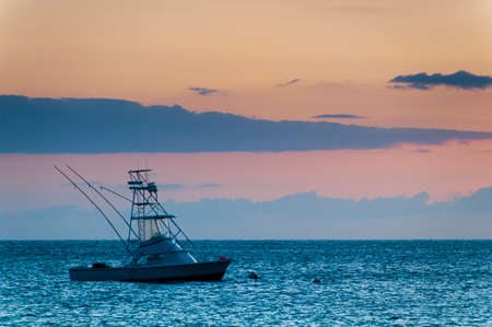 Beautiful sunset behind sport fishing boat with a flying bridge on Maui, Hawaii, USAの写真素材