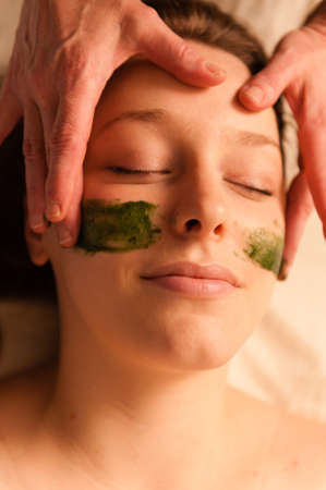 Beautiful young woman receiving a facial massage in a spa 