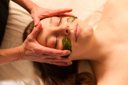 Beautiful young woman receiving a facial massage in a spa の写真素材