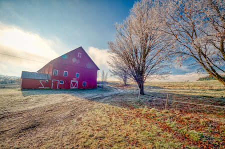 Red barn on a frosty autumn morning in the New England town of Stowe Vermont USAの写真素材