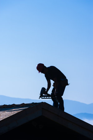 Silhouette of man working on a roof, Stowe, Vermont, USA