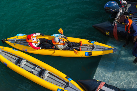 Tourists getting in inflatable ocean kayaks, Hornsund, Norway