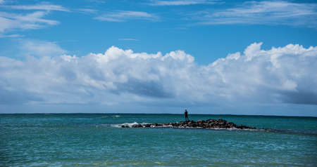 Man stands alone looking out over the ocean
