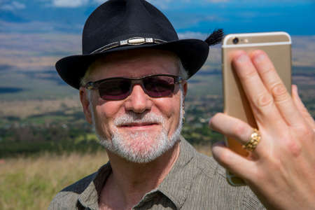 A man in his 60's with a hat taking a selfieの写真素材